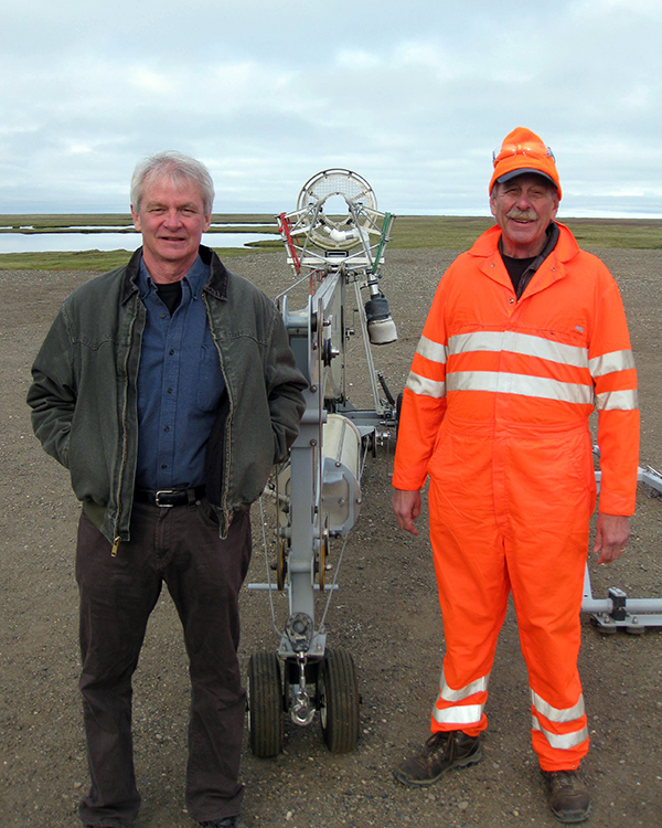 Sandia researcher Mark Ivey, left, and Sandia safety-basis engineer Al Bendure stand next to a folded SkyHook unmanned-aircraft catcher at Oliktok Point. The Arctic tundra stretches out behind them. (Photo courtesy of Brian O’Kronley, Fairweather LLC)