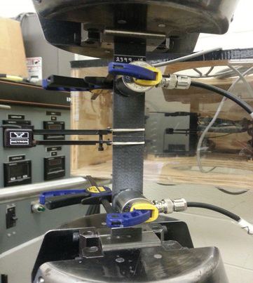Tensile coupon showing acoustic sensors clamped onto sample along with extensometer.