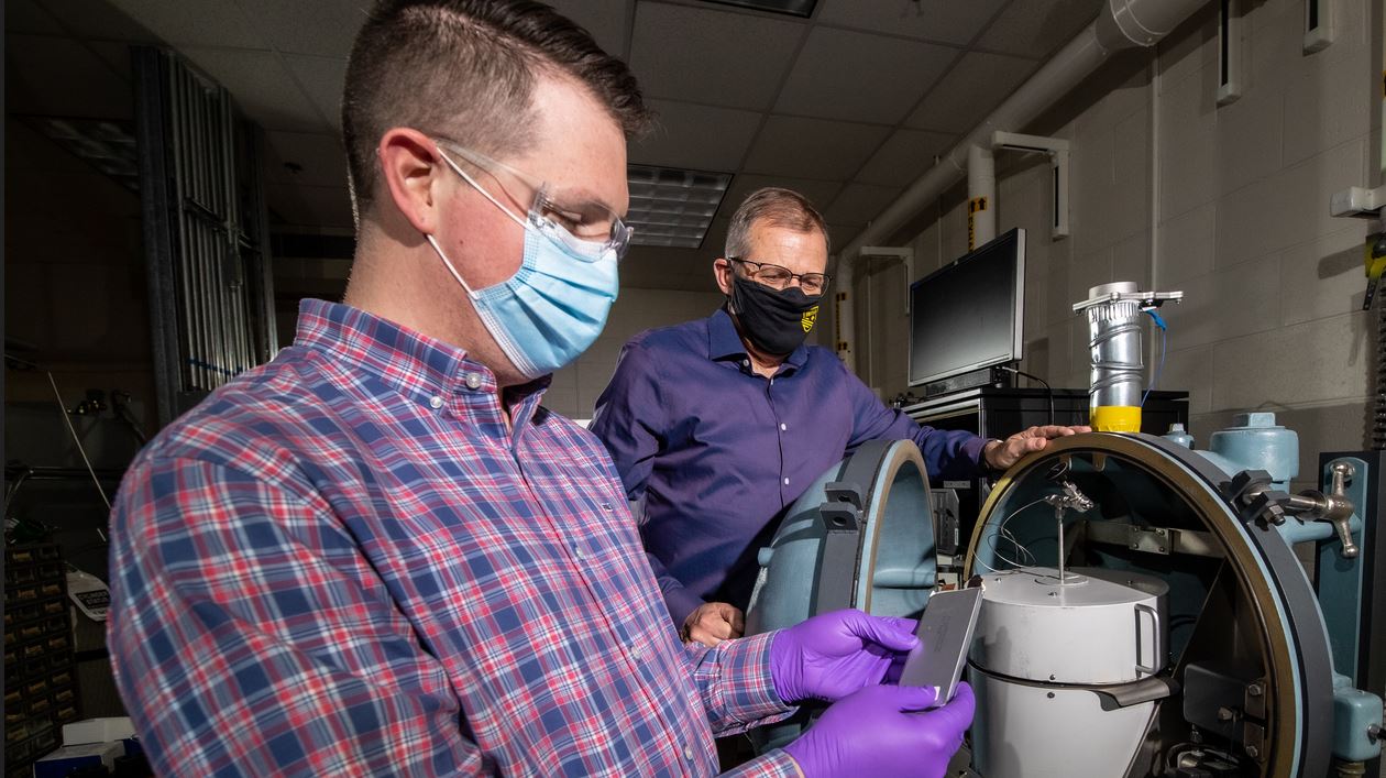 Sandia National Laboratories engineers, examine a lithium-ion battery in front of a specially designed battery testing chamber.