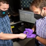 Two Sandia engineers examine a wafer will an array of diodes