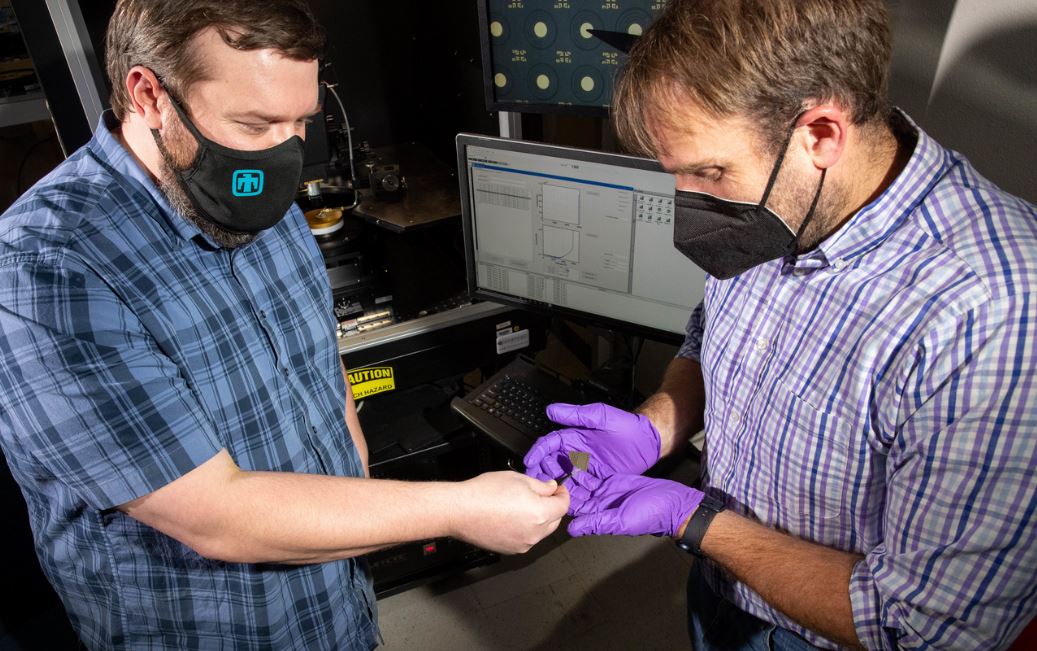 Two Sandia engineers examine a wafer will an array of diodes
