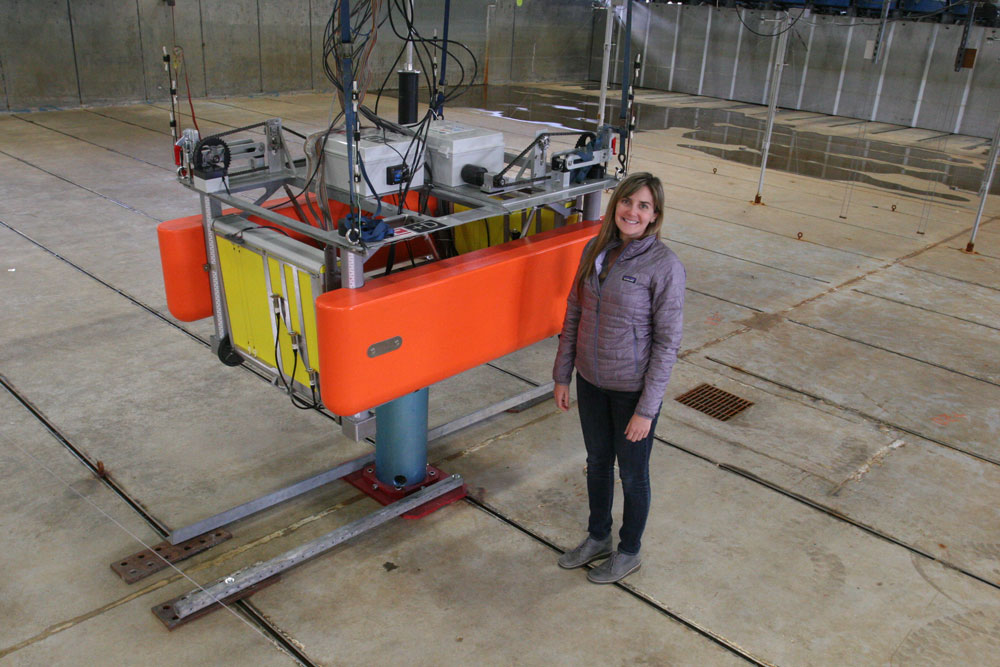 Kelley Ruehl, Sandia National Labs Energy Water Systems Engineer, standing next to an ocean wave energy converter.