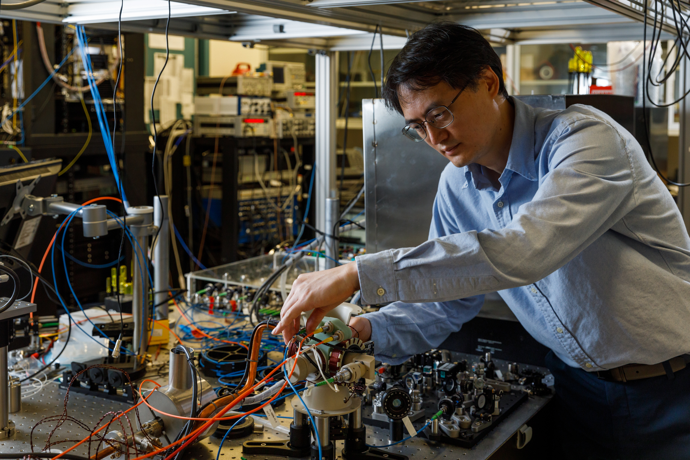 Sandia National Laboratories atomic physicist Jongmin Lee examines the sensor head of a cold-atom interferometer that could help vehicles stay on course where GPS is unavailable. (Photo by Bret Latter)