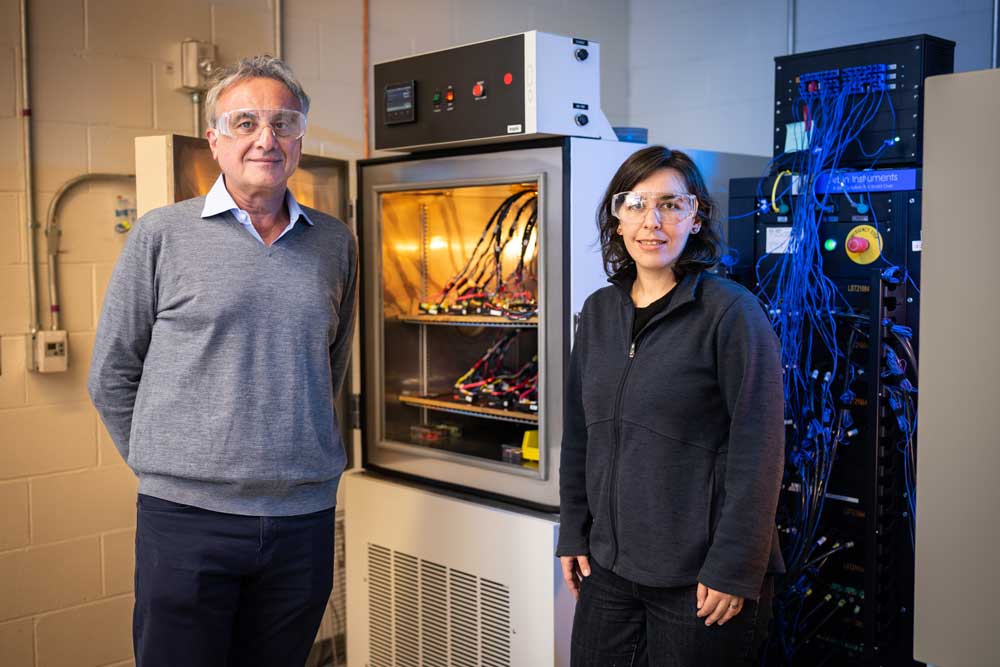 Two researchers stand by battery testing equipment