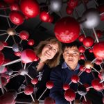 Two researchers peer through an artistic representation of the chemical structure of a kind of clay