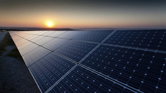 Photovoltaic solar panels gleam against the backdrop of a setting sun