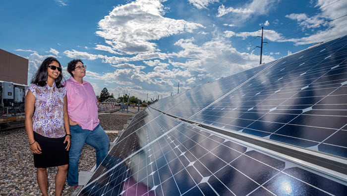 Two researchers stand adjacent to a photovoltaic solar panel at Sandia's Photovoltaic Systems Evaluation Lab
