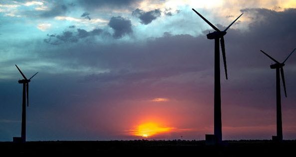 three wind turbines outlined by a luminous sunset at the Sandia Wind Farm Testing Facility