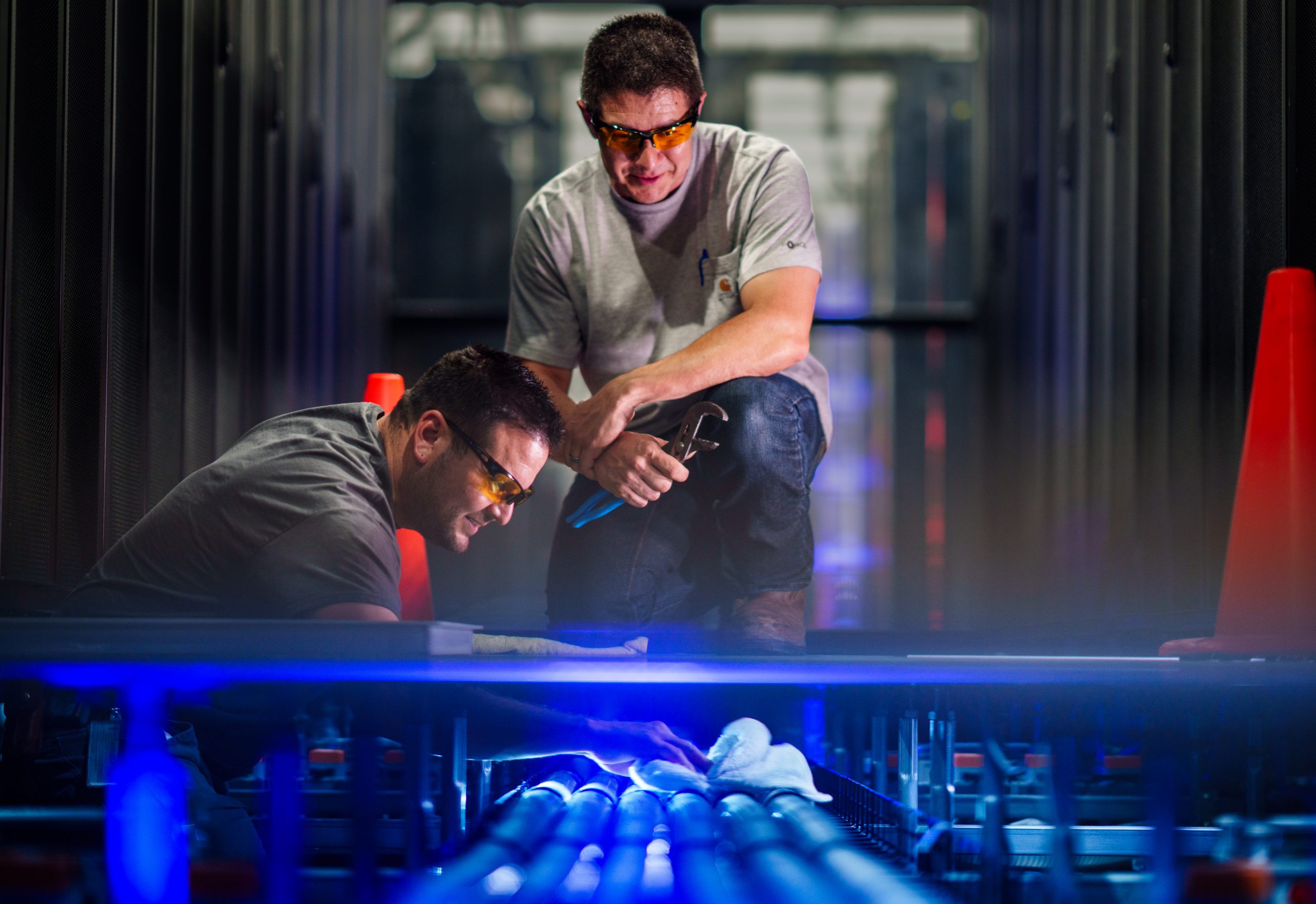 Two men check the liquid cooling system in Sandia's high performance computing building.