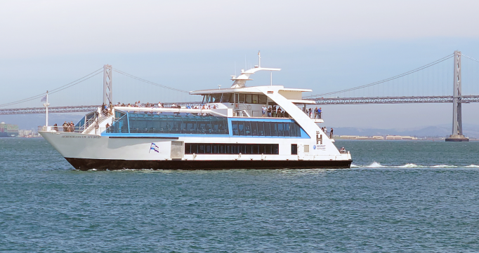 A passenger ferry, titled Discover Zero, crosses an open bay of the coast of California. A suspension bridge appears in the background.